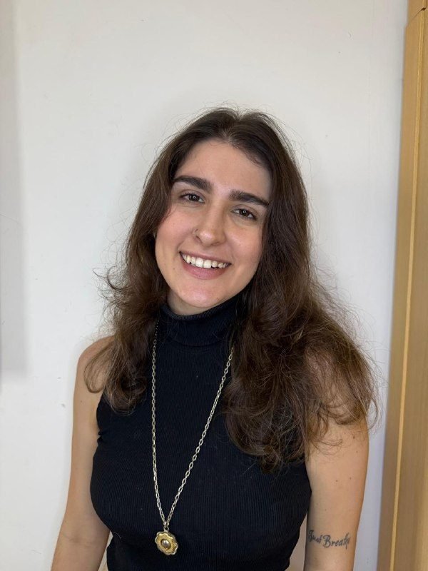 Retrato da psicóloga Luiza Noronha, sorrindo, de blusa preta